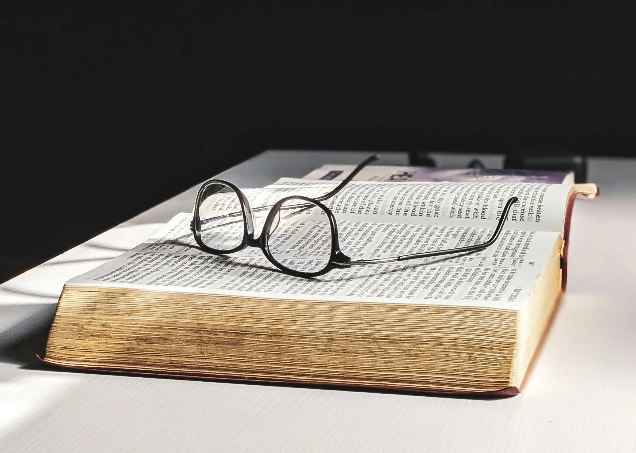 Libro abierto con unas gafas de lectura encima