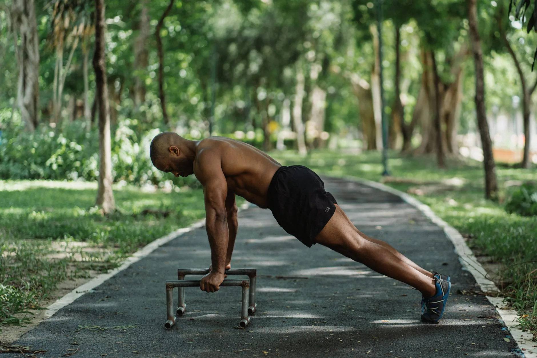 topless man doing push up on low dip bars