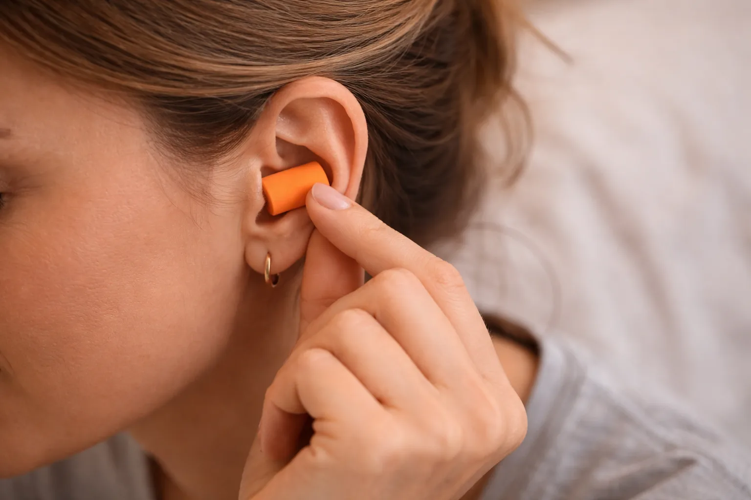 Persona colocando tapones para dormir en el oído, mostrando cómo se usan para reducir el ruido diario