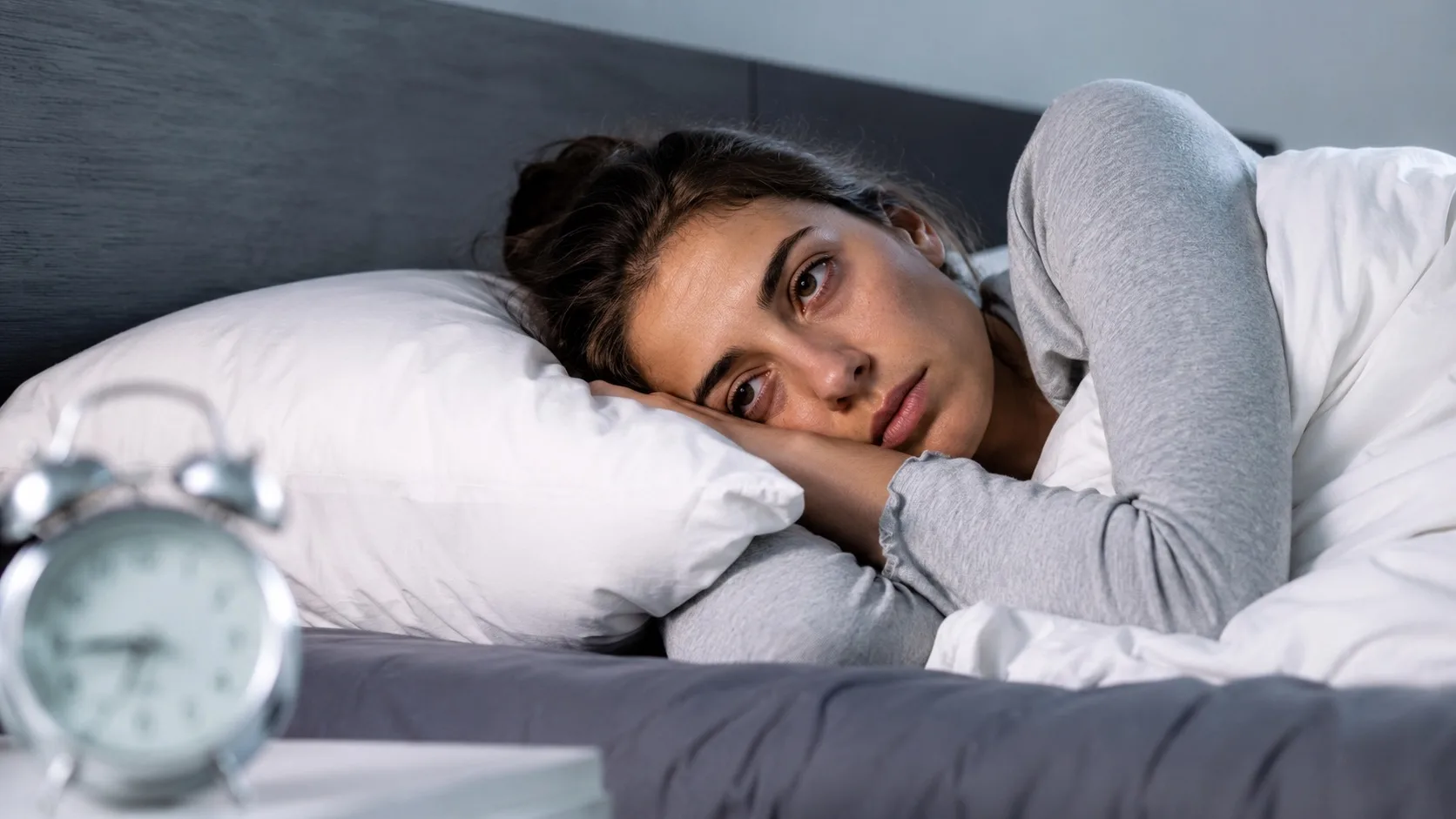Persona acostada en la cama con aspecto de cansancio y somnolencia a pesar de haber dormido ocho horas, ilustrando los problemas de sueño y descanso insuficiente.